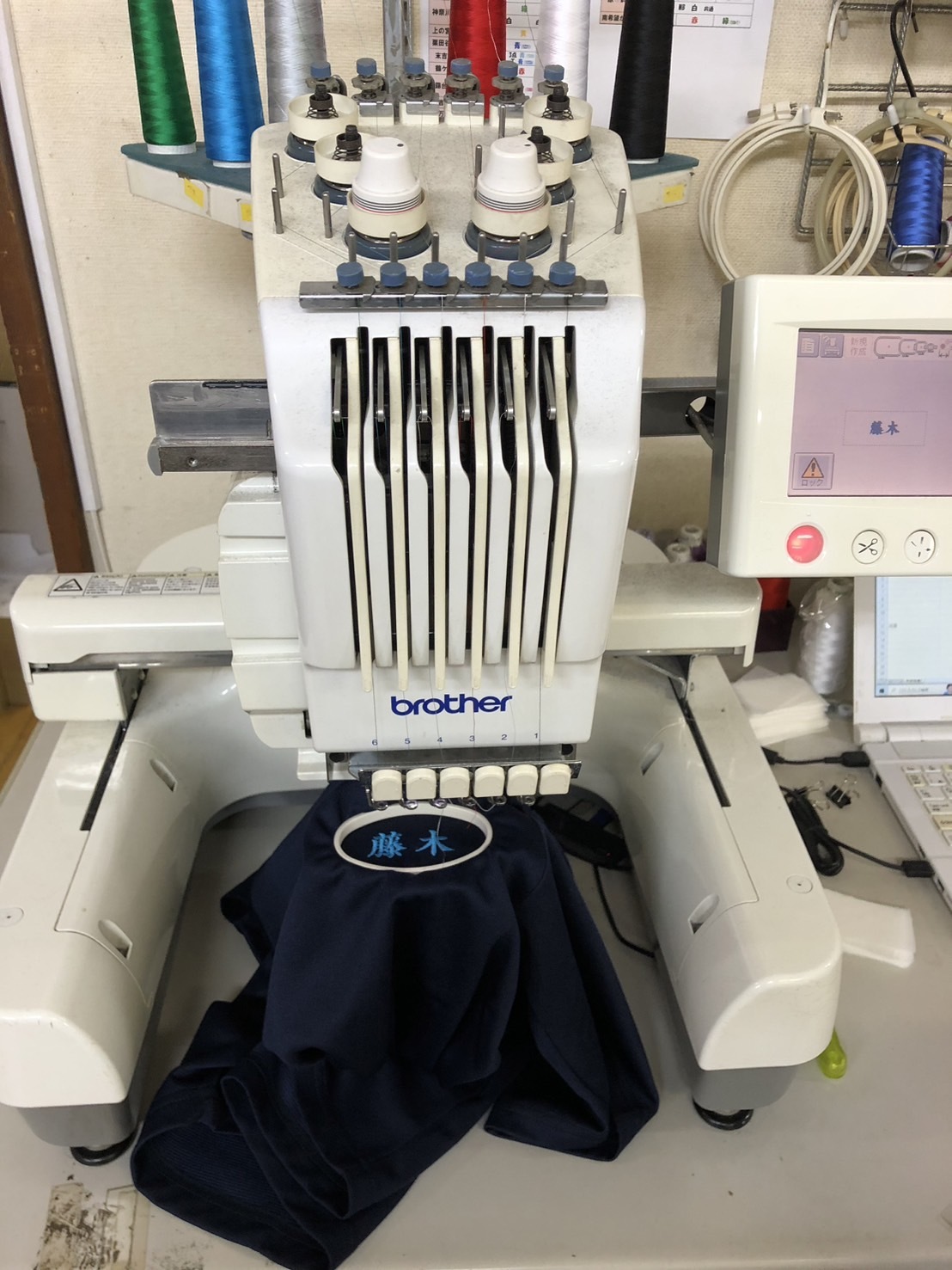 写真：黒い服に名前の刺繍を入れているところ